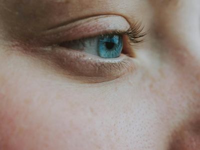 Person taking a deep breath with closed eyes in a calm setting.